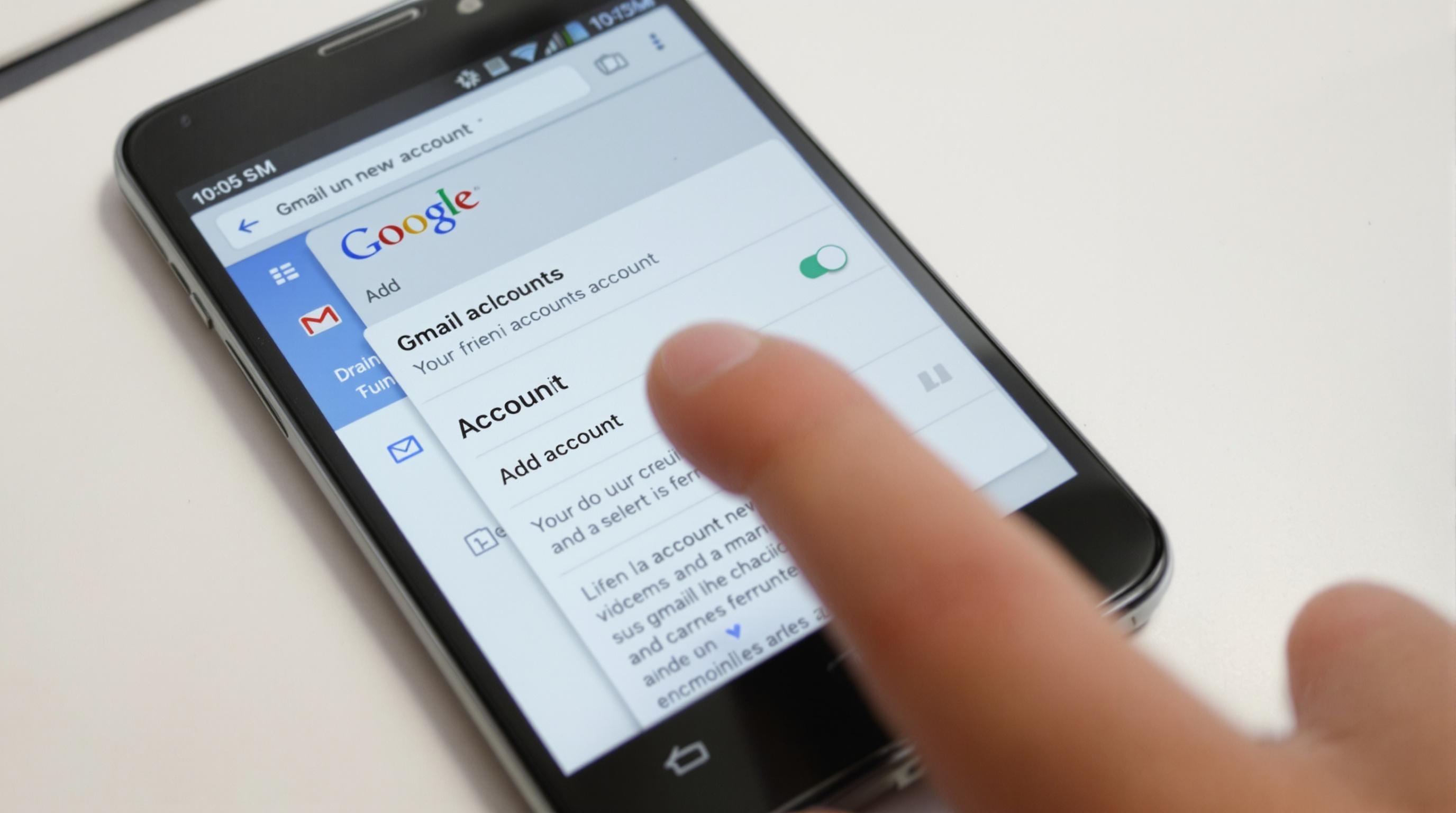 Smartphone Android montrant le sélecteur de comptes dans l’appli Gmail, doigt pointant vers « Ajouter un compte ».